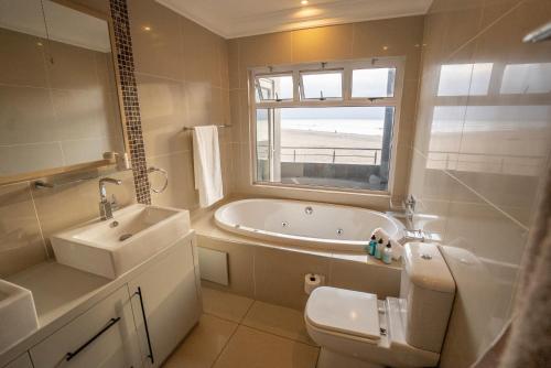 a bathroom with a tub and a sink and a toilet at Deja Blue Beachfront Villa, Newly renovated in Langstrand
