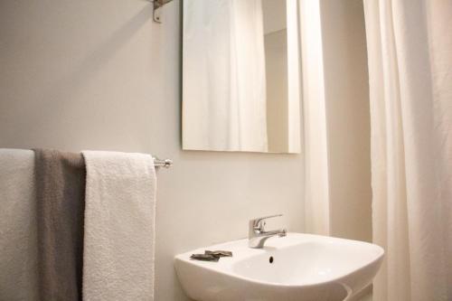 a bathroom with a sink and a mirror and towels at Apartamentos Central in Quarteira