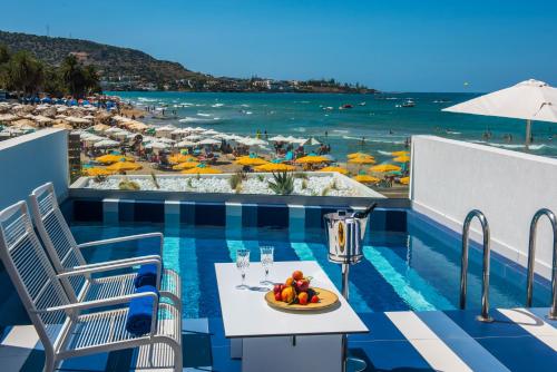 una mesa con un bol de fruta en el balcón con una playa en I Resort Beach Hotel & Spa en Stalida