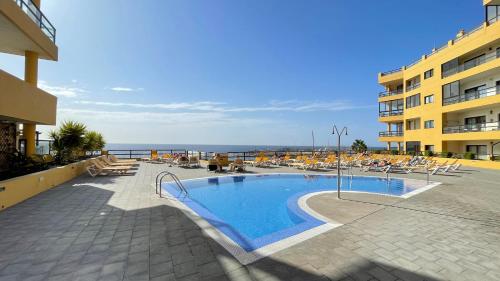 una piscina en un complejo con sillas y el océano en Ocean Golf, en San Miguel de Abona