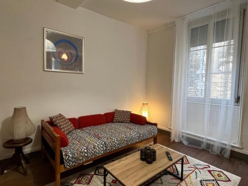 uma sala de estar com um sofá vermelho e uma mesa em Jupiter YourHostHelper em Caen