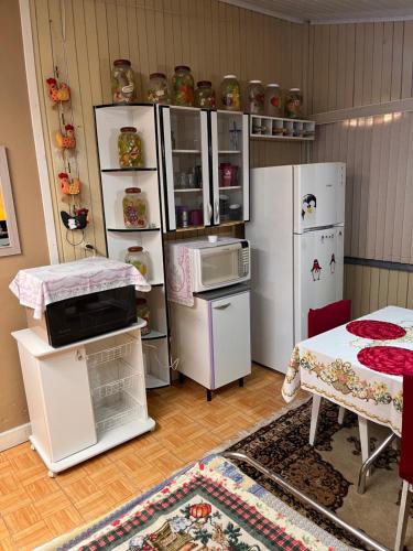 una cocina con electrodomésticos blancos y una habitación con mesa en Casa Estrela Guia en Urubici