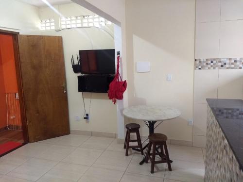 a kitchen with a table and stools and a tv at Kitnets casa Amarela Imbassai in Imbassai