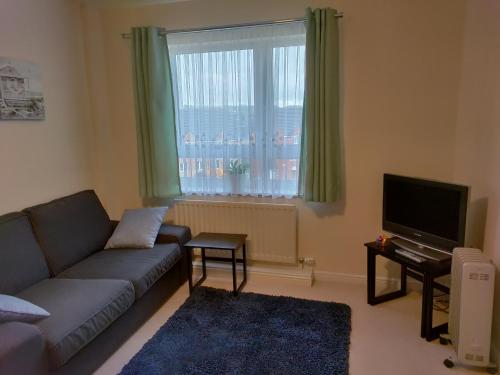 a living room with a couch and a television at Double Room in a Top Floor Shared Apartment in Northampton