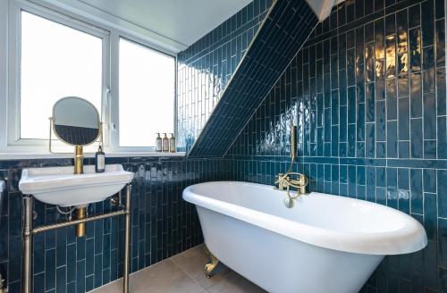 baño de azulejos azules con bañera y lavamanos en The Anchorage, en Poole