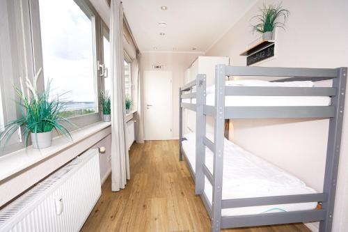 a bunk bed in a room with windows and plants at Penthouse Hygge mit Meerblick & Schwimmbad am Hansapark für Familien in Sierksdorf