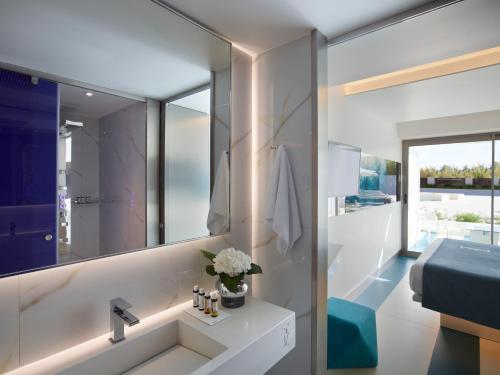 een badkamer met een wastafel en een spiegel bij I Resort Beach Hotel & Spa in Stalida
