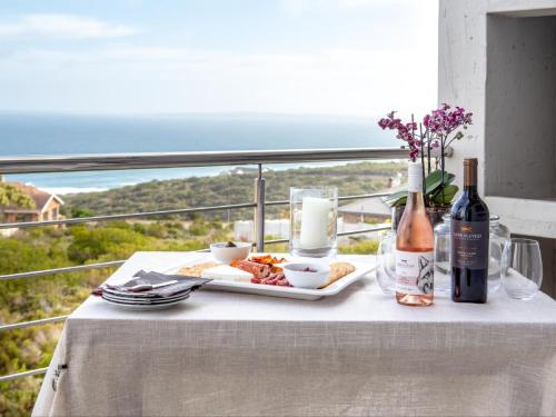 - une table avec une assiette de nourriture et une bouteille de vin dans l'établissement Erika27 B&B NO LOADSHEDDING, à Dana Bay