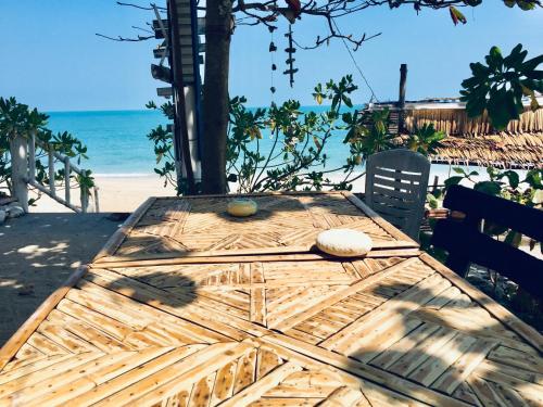 a wooden table sitting on a beach with the ocean at Lamai chalet in Amphoe Koh Samui