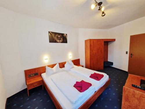 a bedroom with a large white bed with red pillows at Hotel Deutsches Haus in Dingelstädt