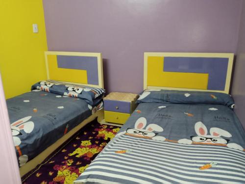 1 dormitorio con 2 camas y kitty Hello en Fekry home en Asuán