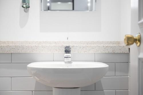 a white sink in a white tiled bathroom at Miller & Carter Heaton Chapel by Innkeeper's Collection in Manchester