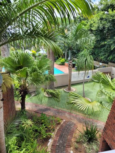 a garden with palm trees and a swimming pool at Perna Perna Lodge St Lucia in St Lucia