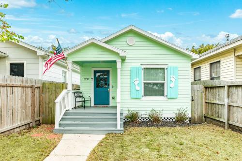 a white house with a blue door and a fence at Barefoot Coastal Cottage in Galveston