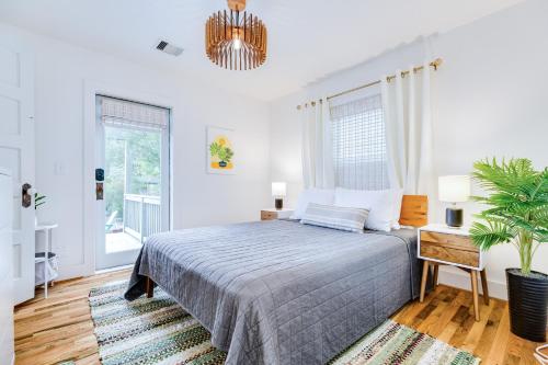 a white bedroom with a bed and a potted plant at Barefoot Coastal Cottage in Galveston