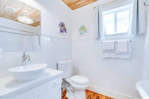 a white bathroom with a toilet and a sink at Barefoot Coastal Cottage in Galveston