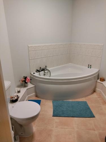 a bathroom with a white tub and a toilet at Double Room in a Top Floor Shared Apartment in Northampton