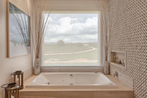 a bath tub in a bathroom with a large window at Casa Mantiqueira Hotel Boutique in Jacutinga