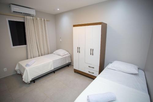 a small bedroom with two beds and a cabinet at Condomínio Villa Belém em Intermares por Carpediem in Cabedelo