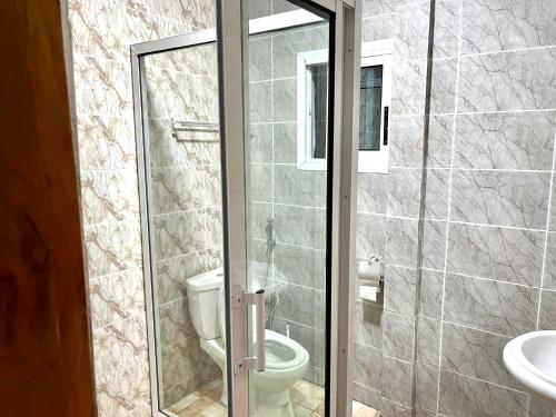 a bathroom with a toilet and a glass shower door at Swiss Cottage in Kribi