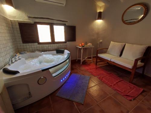 una grande vasca da bagno in una camera con divano di Cortijo Aldamuz a Oria