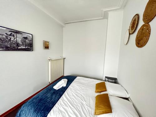 - une chambre blanche avec un lit et des oreillers jaunes dans l'établissement Mon Spacieux Studio Parking Un-Séjour-à-Part, à Saint-Julien-lès-Metz