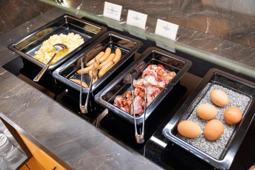 two trays of food on a counter with eggs at Hotel Nele in Ziano di Fiemme