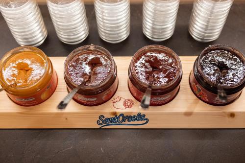 four jars of peanut butter and jelly on a wooden tray at Hotel Nele in Ziano di Fiemme