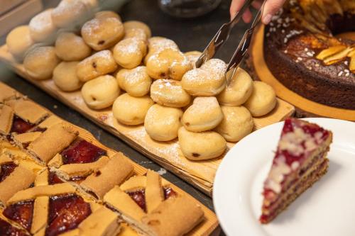 a person cutting a piece of cake and other pastries at Hotel Nele in Ziano di Fiemme