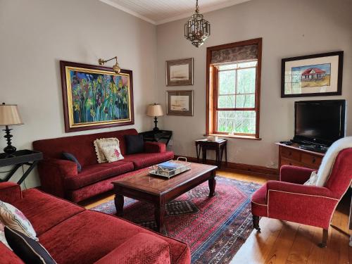 a living room with red couches and a coffee table at St Aidan's Manor in Grahamstown