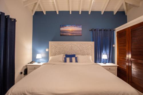 a bedroom with a large white bed with blue walls at Reflection Y 5 Star Villa in Maho Reef