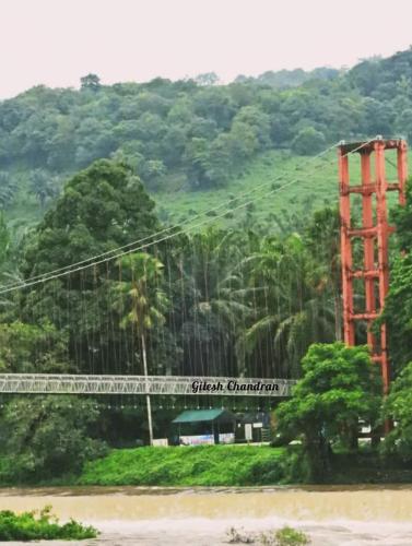 a bridge in front of a hill with trees at RAIN DROPS PREMIUM VILLAS - Athirappilly in Athirappilly
