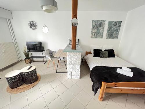 a bedroom with a bed and a table and a tv at Vue sur Jardin Parking Ascenseur Un-Séjour-à-Part in Metz