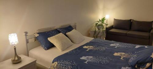 1 dormitorio con cama con sábanas azules y sofá en Pakeliui, en Kaunas