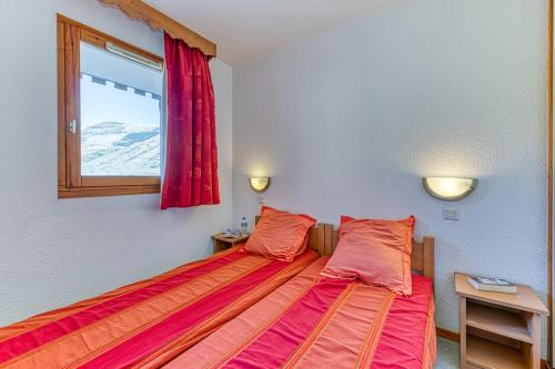 Un dormitorio con una cama con sábanas rojas y una ventana. en Les Balcons du Soleil 4013, en Les Deux Alpes