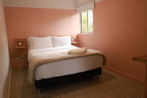 a bedroom with a bed with white sheets and a window at Hotel Bania travels in Guatapé