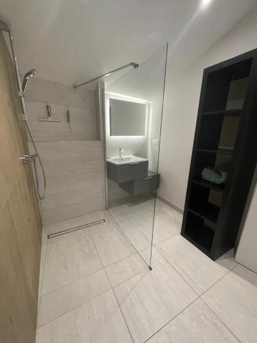 bagno con doccia, lavandino e specchio di Villa des Huniers à La Chaume a La Chaume