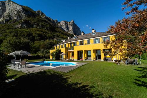 ein gelbes Haus mit Pool im Hof in der Unterkunft Montebello in Lecco