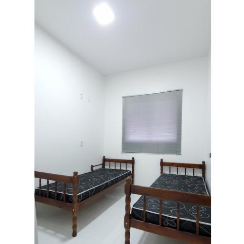 two beds in a room with a window at BALNEÁRIO GAIVOTA no AREIAS CLARAS in Sombrio