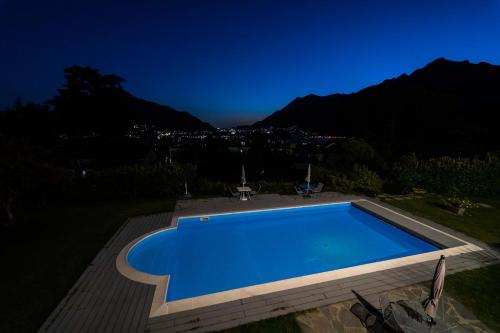 a blue swimming pool at night with mountains in the background at Montebello in Lecco
