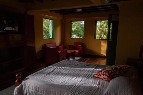a bedroom with a bed and two windows at Hotel El Eden Country in Armenia