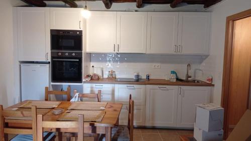 cocina con armarios blancos y mesa de madera en El Nogal en Bubión