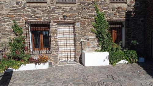 a stone building with two windows and some plants at El Nogal in Bubión