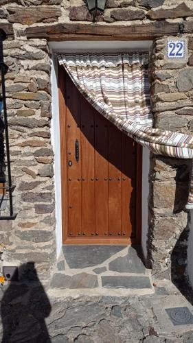 a wooden door in a stone building with a stone wall at El Nogal in Bubión