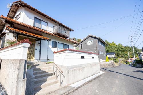 una casa blanca con escaleras en una calle en 湯庵 完全貸し切り庭付き, en Matsue