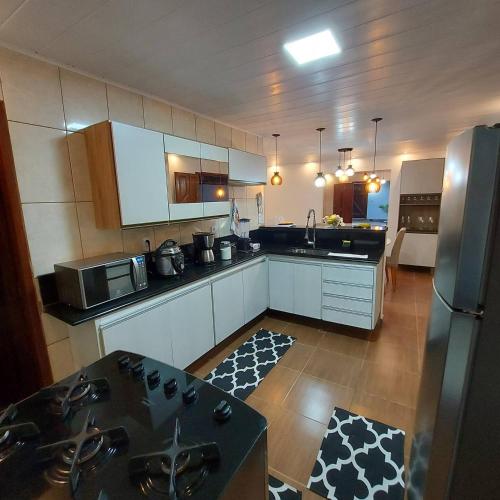 a kitchen with white cabinets and a stainless steel refrigerator at Residência Thomas in Itacaré