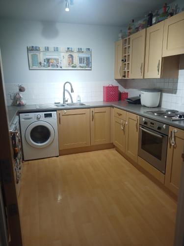 a kitchen with a sink and a washing machine at Double Room in a Top Floor Shared Apartment in Northampton