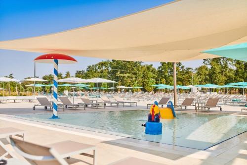 a pool at a resort with chairs and umbrellas at Easyatent Safari tent Park Umag in Umag