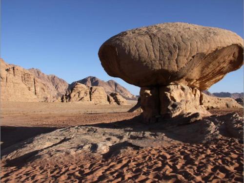 a large rock in the middle of the desert at Sunset Mountain in Wadi Rum