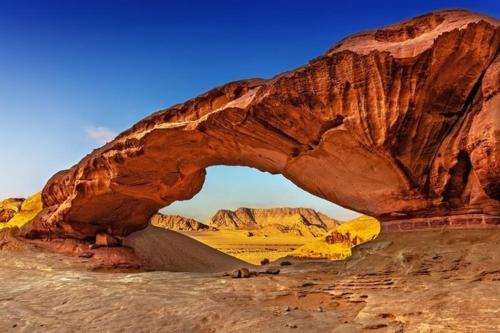 Une arche rocheuse dans le désert avec une route en dessous dans l'établissement Sunset Mountain, à Wadi Rum